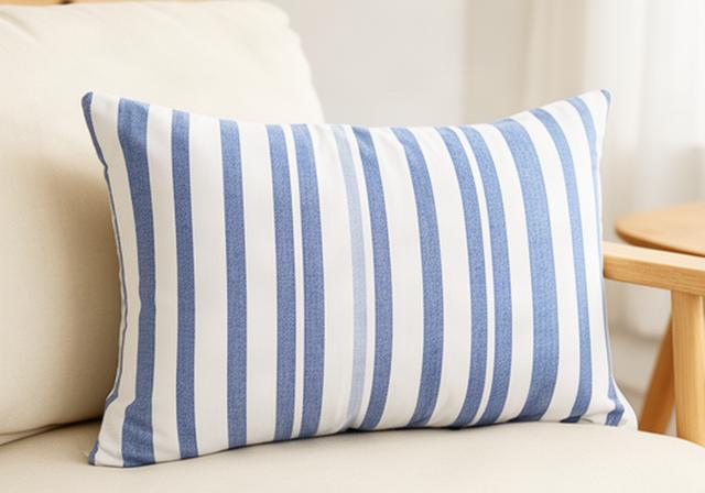 Katoenen sierkussen met blauwe strepen op een crèmekleurige bank in een rustige woonkamer